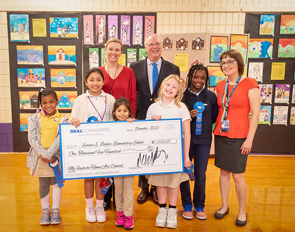 Neal Communities Pat Neal (center), founder and chairman of Neal Communities, with Emma E. Booker Elementary School principal Cameron Parker (left), art teacher Melissa Shaw (right) and top winners from the “My Favorite Home” art contest.